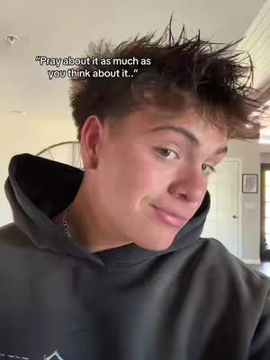 A young man with short, spiky brown hair is the focus. He's wearing a dark hoodie, and the background suggests a domestic setting. Text overlayed at the top says, "Pray about it as much as you think about it." He's looking towards the camera with a slight smile.