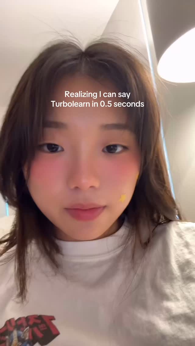 A young woman with brown hair and blush is centered in a close-up shot. She is wearing a white t-shirt and has a small yellow star sticker on her left cheek. Text overlayed on the image reads "Realizing I can say Turbolearn in 0.5 seconds". The background is blurred.