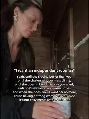 A woman is shown from the chest up, slightly angled, in front of a rustic interior. She looks down and to the side, with a thoughtful expression. A text overlay with a quote is in the lower portion of the frame. The color palette is muted and natural, with browns and blacks dominating.