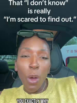 A woman is centered in the frame, likely inside a car. She has dark hair and is wearing a yellow top, and sunglasses are perched on her head. Text overlays appear at the top and bottom, the background includes car elements and a TESLA charging station sign in the background.