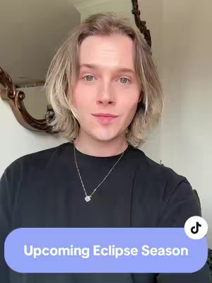 A portrait shot of a person with blonde hair wearing a black shirt and a silver necklace. The background is a plain wall with a decorative mirror. A rounded rectangle with the text 'Upcoming Eclipse Season' is at the bottom of the image.