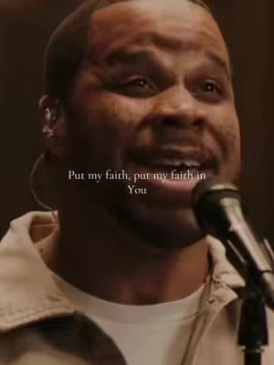 The cover image features a close-up shot of a Black man singing into a microphone. The background is blurred, focusing on the man and the microphone. Overlayed text reads, in a clean font, 'Put my faith, put my faith in You'. The color palette is warm, with natural skin tones and a dark background, suggesting a stage or performance setting. The composition centers on the man's face and the microphone, highlighting the act of singing.