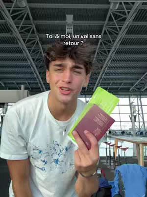 A young man in a white t-shirt stands in an airport setting, smiling. He is holding a passport and a green document. The background shows the airport structure.