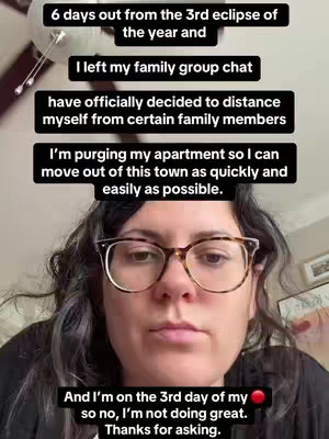 A medium shot shows a woman with glasses looking directly at the camera. Above her head are multiple black text boxes with white text. Below the text boxes is the woman's face. The background is out of focus, with a ceiling fan visible in the top left.