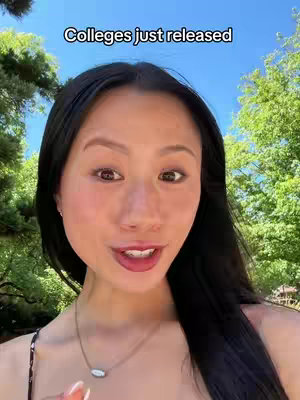 A selfie-style video shows a young Asian woman's face close up. She is in a natural outdoor setting with a blue sky and greenery visible in the background. She's looking towards the camera, engaging the viewer with a direct gaze and slightly parted lips. Above her, the text overlay "Colleges just released" is visible.