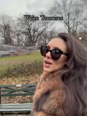 A casual outdoor shot featuring a woman wearing large sunglasses and a fur coat, with a park setting visible behind her. The text "We're Tauruses" is superimposed at the top.