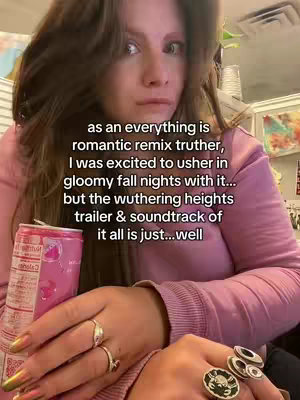 A medium shot of a woman looking at the camera, holding a can of drink in one hand and various rings. The background has a blurred look of an indoor setting. In the image, text overlays on the image.