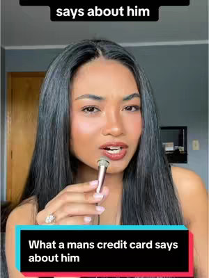 A woman with long, dark hair is holding a small microphone. Text overlays read, "says about him" at the top and "What a mans credit card says about him" at the bottom. The background features a wall and possibly a door or mirror.