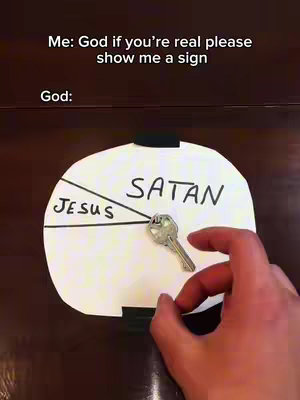 The cover image depicts a humorous setup related to faith. A white, circular piece of paper, divided into segments, forms the central element. The segments are labeled 'JESUS' and 'SATAN', with a key placed at the center where the segments meet. Above the paper is the text 'Me: God if you're real please show me a sign' and below 'God:'. A hand is seen touching the paper.