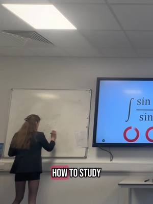 A woman with long, light brown hair is standing in front of a whiteboard and a large digital display. She is wearing a black blazer and short skirt writing on the whiteboard with the text "HOW TO STUDY" overlaid on a pink background.