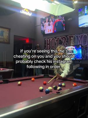 The image shows a person holding a pool cue, poised to hit a ball on a pool table. The table and balls are in the foreground. In the background, there is bar setting with a large screen TV showing a basketball game. Above the TV is the word "Hollz" lit up and next to an image of a sports team in action. Overlay text is present on the image, in a simple white outlined font, appears to be instructions about checking Instagram. The lighting is dim with a warm, inviting glow. The overall focus is on the pool and advice being given.