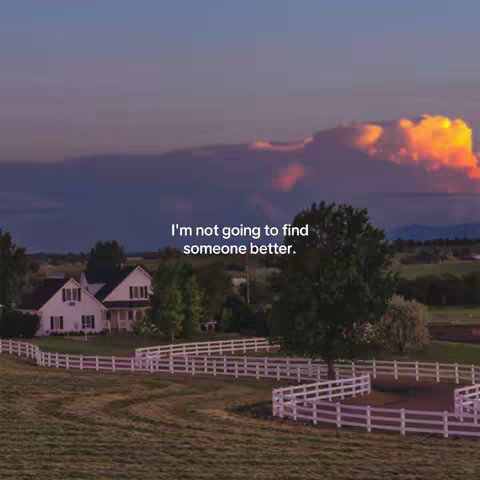 An idyllic landscape with a white-fenced horse ring, a large white house and a vibrant sunset sky with clouds.