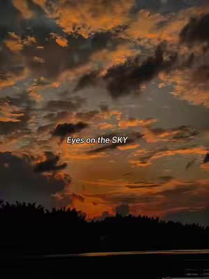 A sunset over a body of water with a treeline in the foreground. The sky is filled with orange and gray clouds with the text "Eyes on the SKY" overlaid in the center.