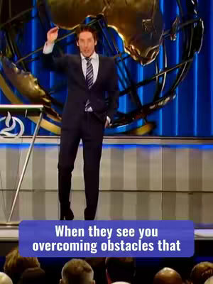 The image features a man standing on a stage, gesturing with his right hand. Behind him is a shimmering gold structure, perhaps part of the stage design, against a blue backdrop. A text overlay in a blue box at the bottom reads, “When they see you overcoming obstacles that”. The man is wearing a dark suit with a tie.