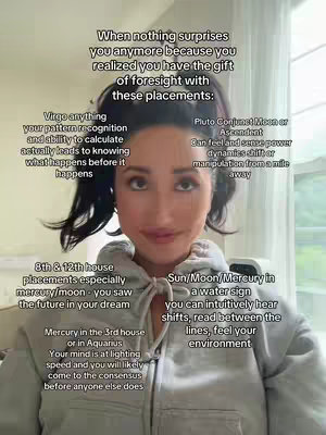 A selfie-style shot featuring a woman centered in the frame, with text overlays describing astrological birth chart placements. She's in a casual hoodie, and the background has soft lighting.