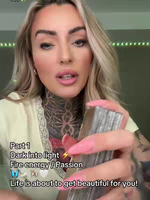 A medium shot features a woman with long blonde hair and heavy makeup, centered in the frame. She is holding a deck of cards that are silver-colored. The background lighting is green and the clothing is a light-colored short-sleeved top. Below near the bottom edge of the image, is added text. The overall composition is visually engaging due to the use of a bright color palette.
