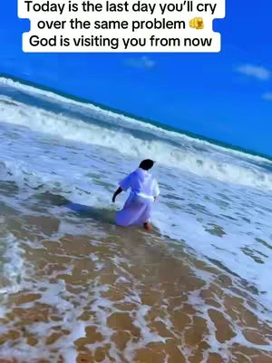 A scenic shot of a beach featuring the ocean, sandy shore, and a person walking into the water. The sky is a vibrant blue.