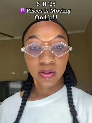 A selfie-style shot featuring a woman with stylish clear-framed glasses, framed by dark pigtail braids. The top carries a text overlay with the date and a message, while the background suggests an interior setting.