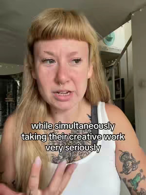 A person with short, tousled, blonde hair and a nose ring speaks directly to the camera. The person wears a white tank top and has tattoos on their upper arm and chest. Text overlays the image.