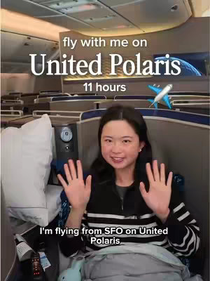 A young woman sits in a United Polaris business class seat on a plane, smiling and holding her hands up in a welcoming gesture. Text overlays describe the flight specifics. The background shows the plane interior.