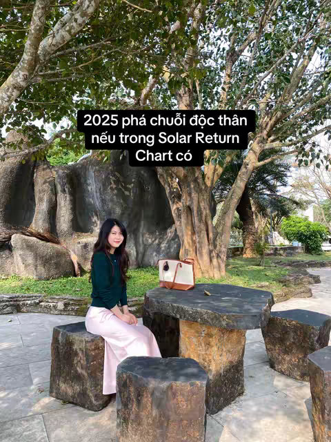 A woman is seated on a stone bench in an outdoor setting. She is surrounded by greenery and trees. A table and other seating elements are adjacent to the woman. Text is overlaid on the image.