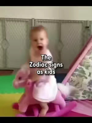 A baby is sitting on a pink rocking horse, with the text overlayed on top, the background is blurred.