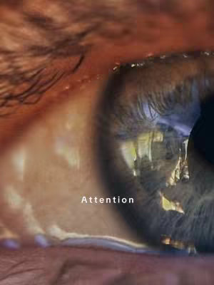Close-up shot of a human eye, with the eyelid and eyebrow partially visible. The eye is the primary focus, with the iris and pupil clearly defined. Visible is an added text overlay that reads "Attention".