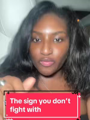 A woman with dark curly hair looks up at the camera, her tongue is sticking out, and she is holding up one finger. A red rectangle with white text that says "The sign you don't  fight with" is in the image in the foreground.