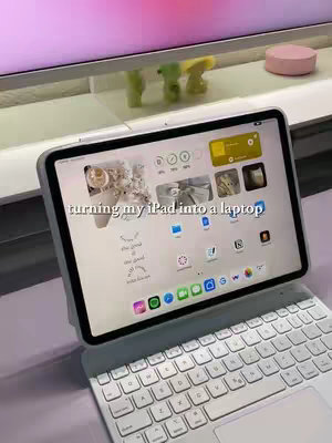 The cover image features a white iPad Pro with a matching keyboard case, positioned on a light purple surface. The iPad screen displays custom app icons. The text overlay reads 'turning my iPad into a laptop'. The background shows a light-colored shelf with small green and yellow figurines.