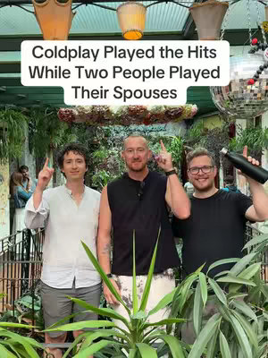 Three men standing in a green outdoor area with foliage. They are each pointing one finger upwards, with the text overlayed in the upper part of the image.