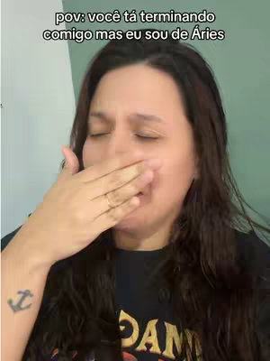 A woman with long, dark brown hair is covering her mouth with her right hand. She has a tattoo on her left forearm. On the cover image, the overlaid text says, "pov: você tá terminando comigo mas eu sou de Áries".