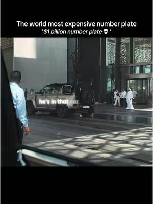 The cover image shows a silver Land Rover with the text 'He's in that car' overlaid on it. Behind the car is a glass-walled building with people in traditional Arab clothing. The sky is overcast.