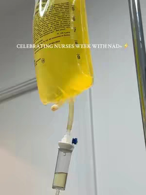 The cover image showcases a medical IV bag filled with a yellowish liquid, connected to a transparent tube and an IV drip chamber. The bag is labeled with white text. The setup is suspended on a silver IV stand against a white wall. The text overlay reads: Celebrating Nurses Week with NAD+ ⚡️