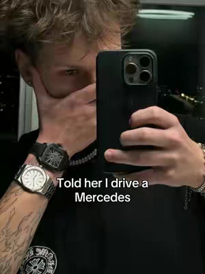 A selfie-style image featuring a young man holding a phone up to his face, partially obscuring it with his hand. He's wearing a black shirt and a watch, with text overlayed at the bottom.