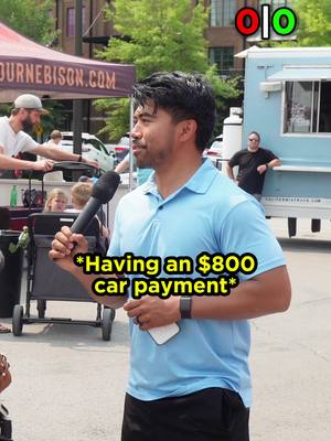A man in a light blue polo shirt stands outdoors, holding a microphone and a phone. The background includes a food truck and buildings, suggesting an urban setting. Text overlayed on the image states 'Having an $800 car payment'.