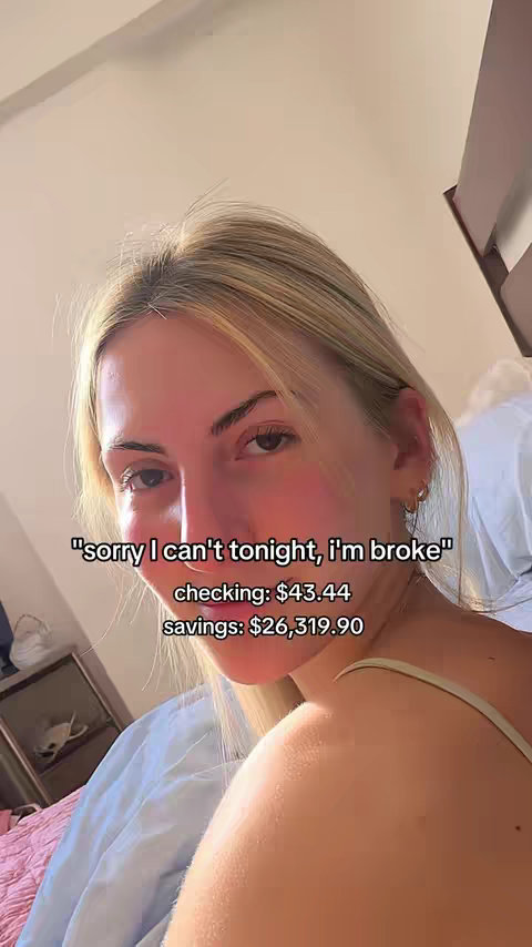 The cover image is a selfie-style shot of a woman. She has blonde hair and is looking at the camera. Overlayed text indicates she's broke, with checking and savings account balances displayed. The background is a bedroom with a bed visible in the periphery.