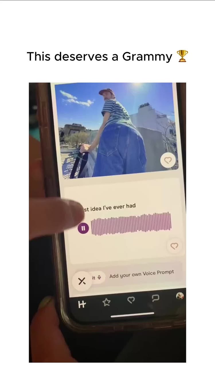 A screen recording shows a phone displaying a social media app interface with a video playing on the screen. The video shows a man from a low angle with his back to the camera, wearing loose jeans and a striped shirt, standing on a rooftop with a bright blue sky and buildings in the background. The phone screen features overlaid text and interactive elements, like a play button and a heart icon indicating a potential like.