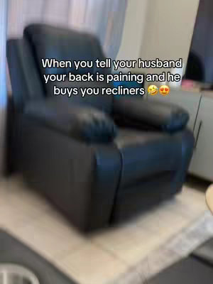The image shows a black recliner chair in a room. The camera angle gives a slightly skewed perspective, and the text overlay is positioned in the middle area.