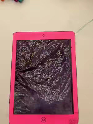 A vibrant, close-up shot showing a pink, hand-drawn tablet or phone, with an expressive, textured black surface covering the screen. The device is set against a clean white background. The tablet has rounded corners. The screen appears to be layered with a semi-transparent paper.