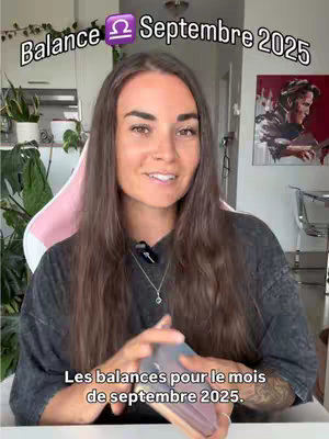 A woman with long brown hair is sitting in a room with plants visible, holding a deck of cards. Text overlay says 'Balance Septembre 2025'. She is smiling and looking at the camera. A pink chair is behind her and in the background is a painting.