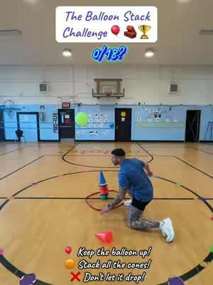 The image shows a man in a gym setting, kneeling on the floor with cones and a balloon. Text overlays at the top read 'The Balloon Stack Challenge' and '0/18?'. Instructions and icons are at the base, explaining the rules: 'Keep the balloon up!' 'Stack all the cones!', and 'Don't let it drop!'