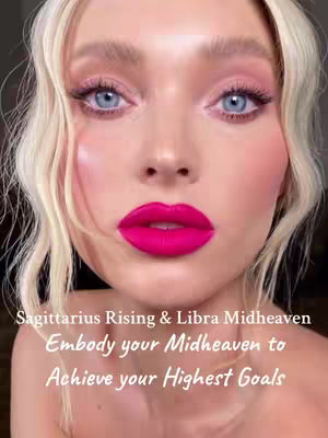 A close-up selfie of a person with blonde hair and light skin. The person's eye makeup includes pink eyeshadow, and their lips are painted a vibrant, hot pink. The image has text overlays at the bottom, and the overall background is blurred.