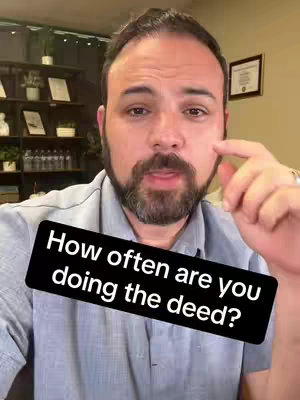 A man with a beard and short brown hair, wearing a blue collared shirt, is looking directly at the camera. In the foreground, a black rectangle with white text overlays the screen. The background consists of a nondescript room with shelves and plants.