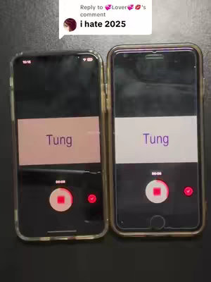 The image showcases two smartphones side-by-side on a dark surface. Each phone displays a recording interface on its screen. The screen background is a light-colored rectangle, with a word like "Tung" centered at the top. Below the colored rectangle, the screen displays black with a red circular record button at the bottom. The phones have clear cases, the background is dark, and there are elements of the phone design visible.
