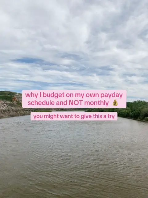 A tranquil scene of a river flowing towards the horizon under a cloudy sky. The water takes up the majority of the frame, with banks visible on either side, and a pink rectangular text overlay with white text floats above the water, toward the center of the frame.