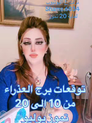 A woman with long brown hair, wearing glasses and a blue top, is centered in the frame. She's set against a blurred background that includes a painting in a gold frame. The overlay text includes Arabic text about astrology.