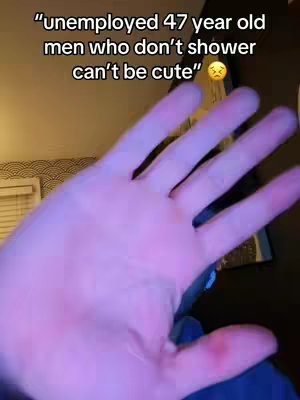 A close-up shot of a person's hand, palm open, with a text overlay. The background is out of focus, with some blurred objects and a wall visible. The hand is lit with a purple hue.
