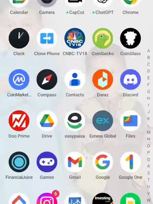 The image shows a phone screen with numerous app icons in a grid arrangement against a blurry background. Several identifiable app icons, including the Exness Global app (ex), are visible. The layout is clean and organized, with a focus on app identification, suggesting a tutorial or instructional context.