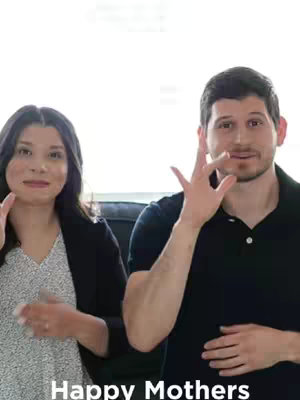 A cover image featuring two people, a woman on the left and a man on the right, signing in American Sign Language (ASL). The woman is wearing a patterned top with a black blazer, and the man is wearing a black polo. The background is a blurred, bright space. The text overlay at the bottom reads 'Happy Mothers'.