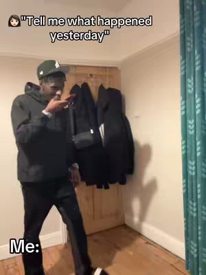 A man in a hoodie and hat mimics reacting to a statement, with text overlay on the image. In the background are coats and a curtain.